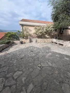 Popločano dvorište sa kamenim zidovima i zelenilom ispred kuće. - image 12