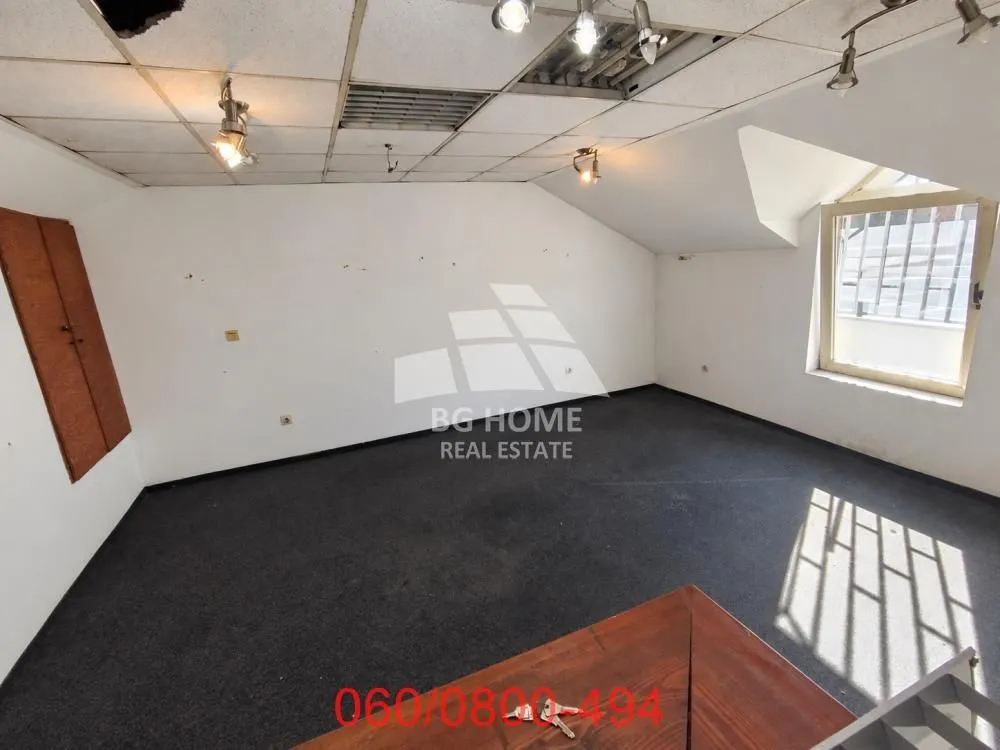 Empty office space with a dropped ceiling, a window, and dark flooring.