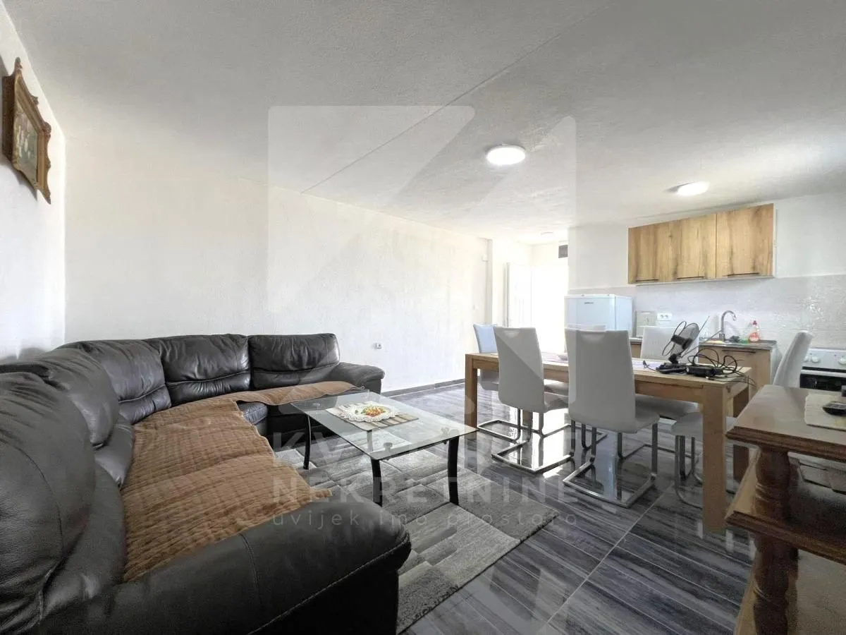 Living room with a sofa, dining area, and kitchen in the background.