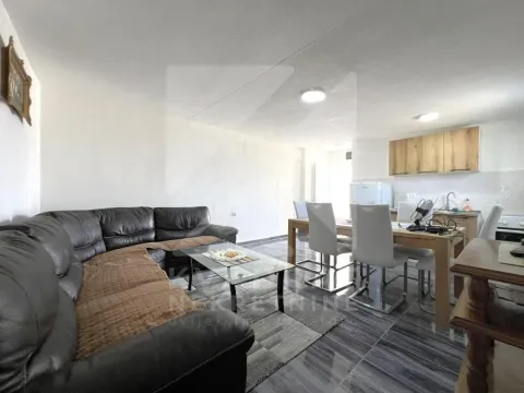 Living room with a sofa, dining area, and kitchen in the background. - image 2