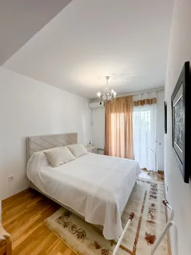 Bright bedroom with a double bed, wooden flooring, and balcony doors. - image 7