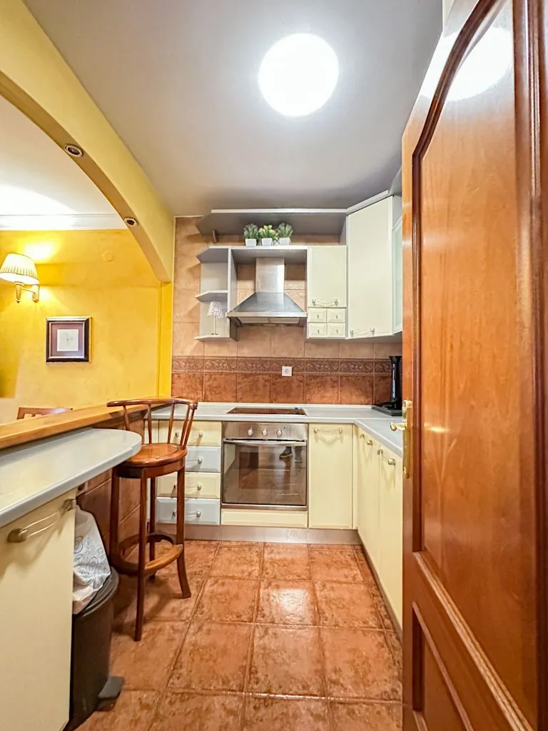 View of a small kitchen with wooden elements and a bar.