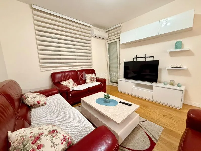 Living room with red leather sofas and a TV unit.