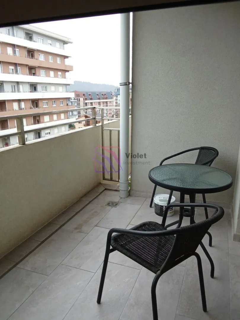 Small furnished balcony with a view of surrounding buildings.