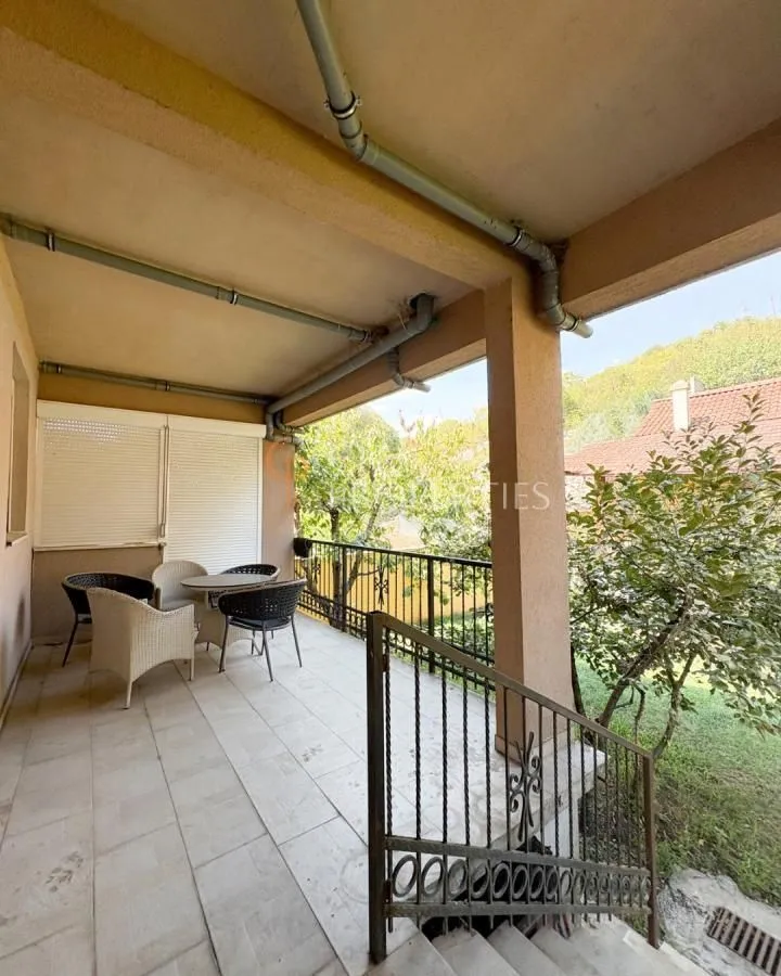 Covered terrace with a table and chairs and stairs leading to the yard.