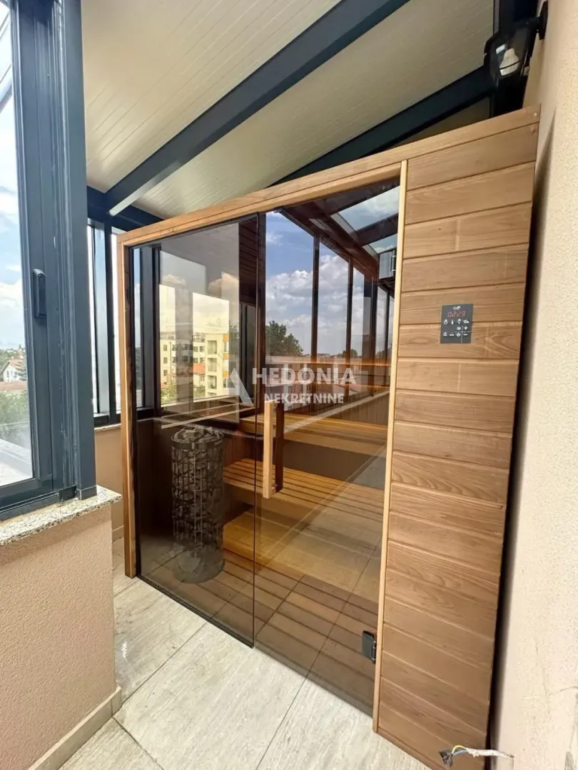 Drvena sauna smeštena na zastakljenoj terasi sa pogledom na okolinu.