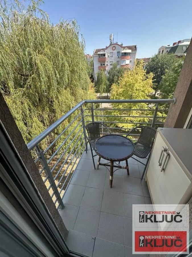 Namešten balkon sa stolom i stolicama i pogledom na zelenilo.