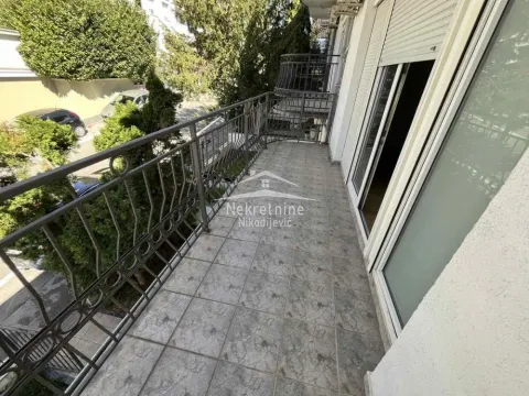 Spacious balcony with tiled flooring, metal railing, and a view of greenery. - image 19