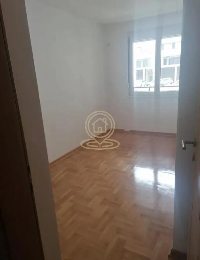 Prazna soba sa parketom i prozorom.