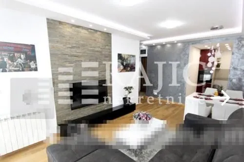 Modern living room with a stone wall cladding and dining area in the background.