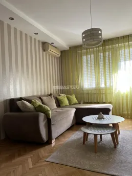 Living room with a corner sofa, small coffee tables, and a window with green curtains. - image 2