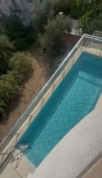 Pogled odozgo na spoljni bazen sa čistom vodom i okolnim zelenilom. - image 2