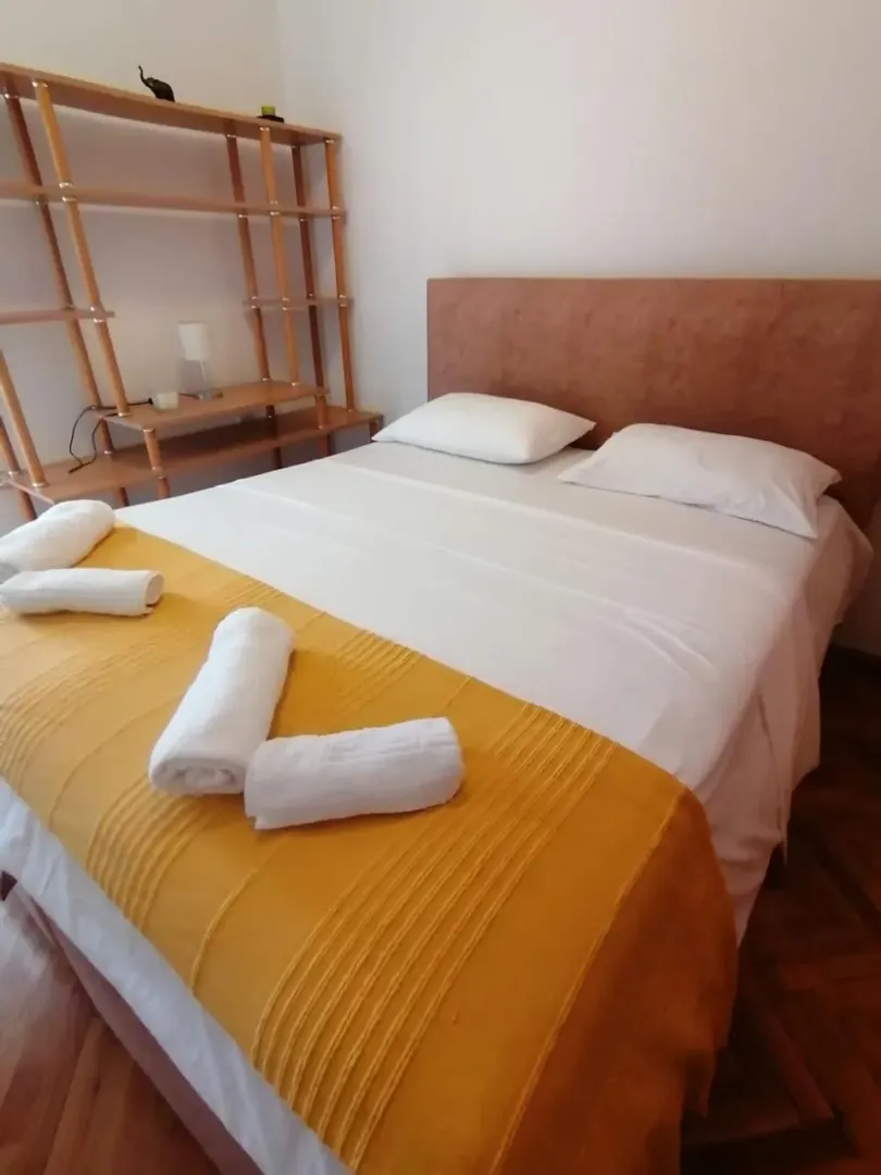 A bedroom with a double bed and a wooden shelf.