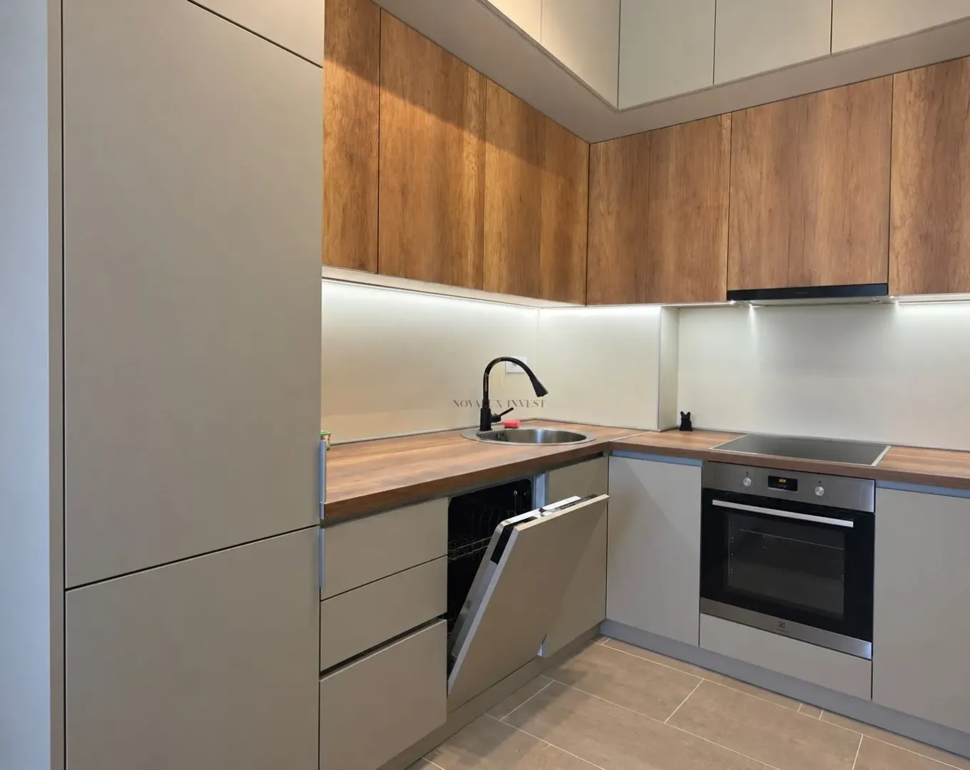 Modern kitchen with wooden cabinetry, built-in oven, and sink.
