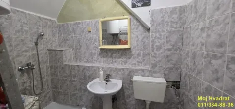 Kupatilo obloženo keramičkim pločicama sa umivaonikom, ogledalom i WC šoljom. - image 8
