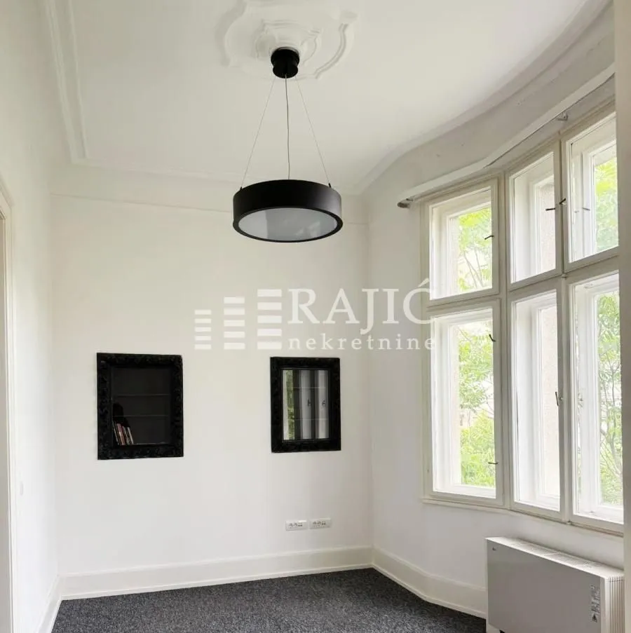 Empty room with large windows and a black chandelier.