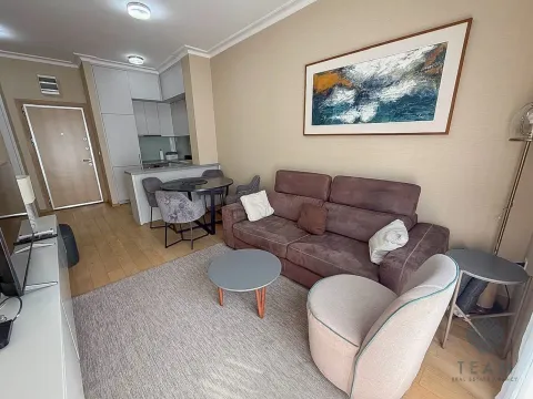 Living room with a sofa, coffee table, and a dining area in the background. - image 2
