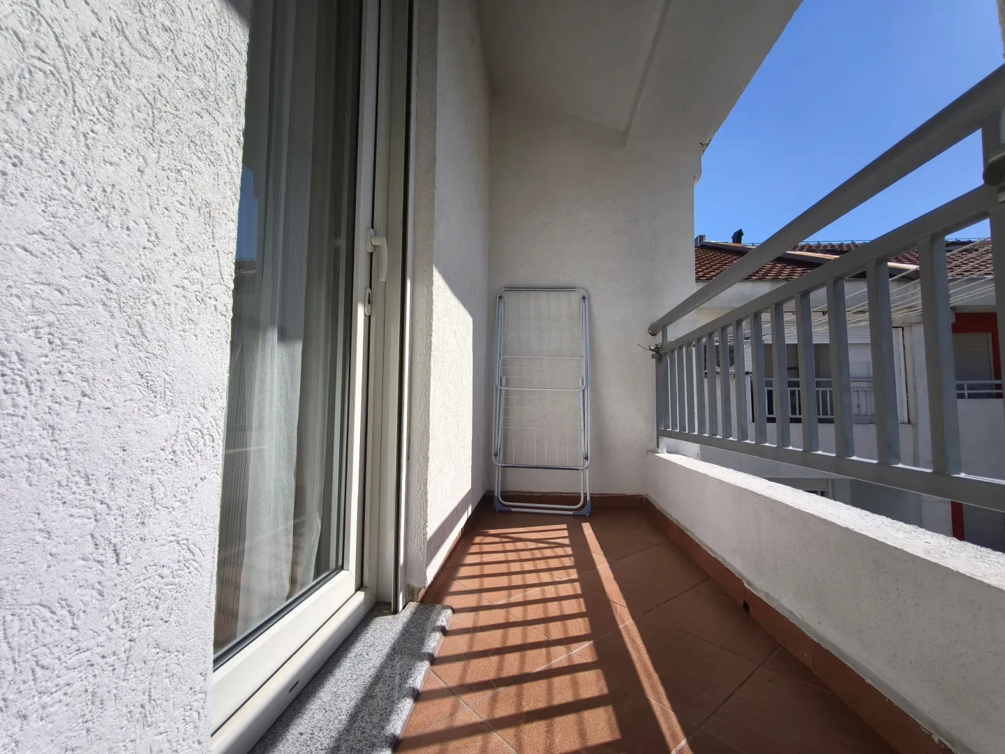 Manji natkriveni balkon sa metalnom ogradom i sušačem za veš.
