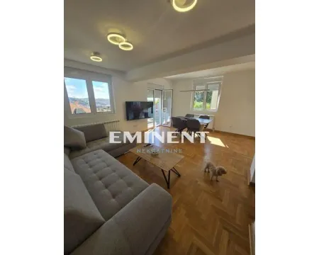 Living room with a sofa, coffee table, and dining area in the background. - image 4