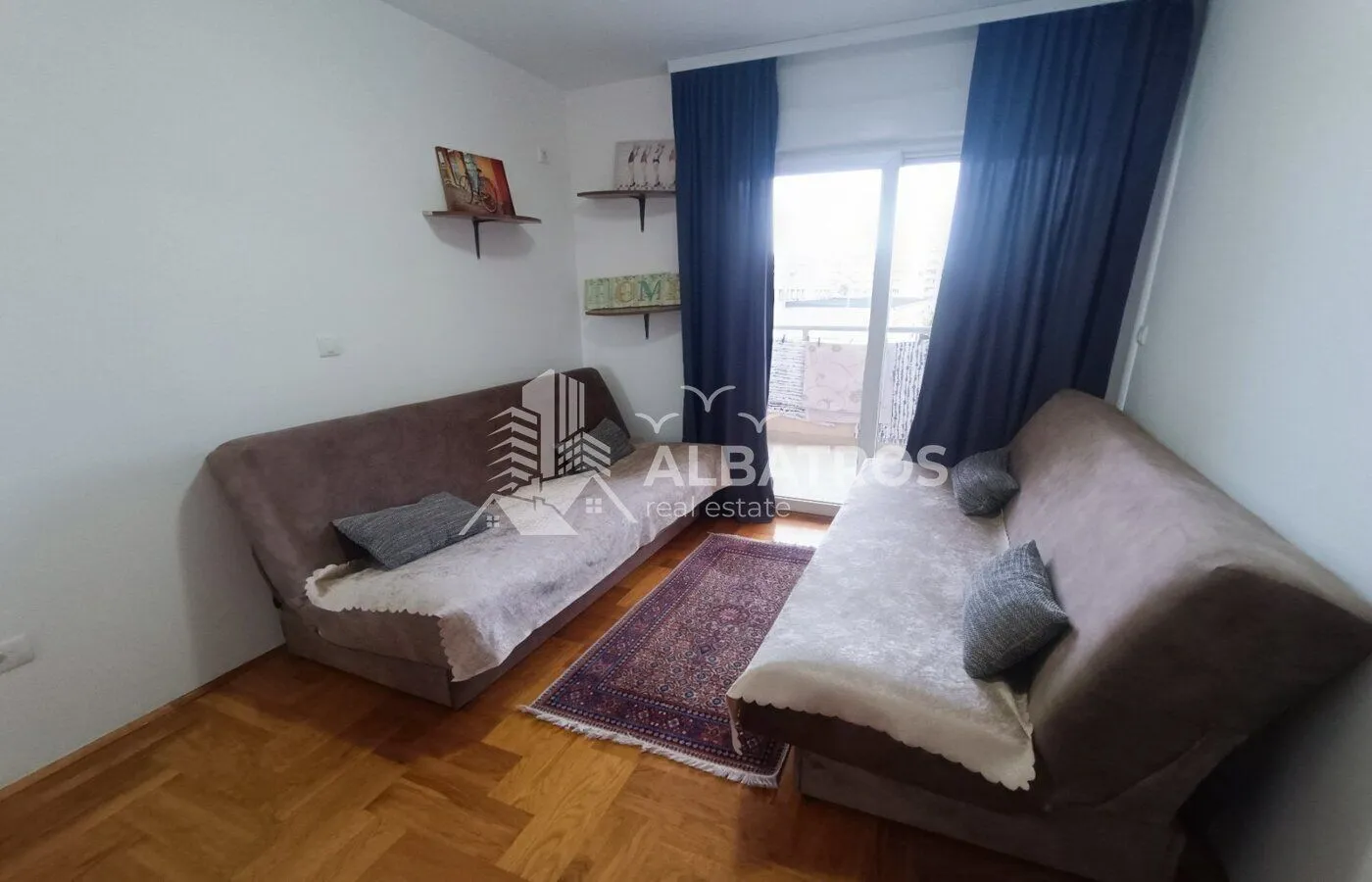 Living room with two sofas, parquet flooring, and balcony access.