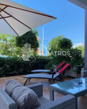Furnished terrace with seating furniture and sun loungers surrounded by greenery. - image 3