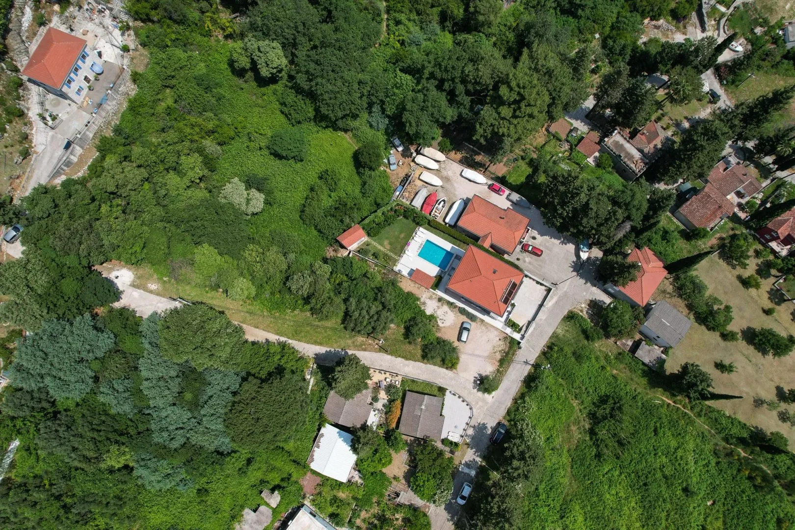 Pogled iz vazduha na kuću sa bazenom i okolno zelenilo.