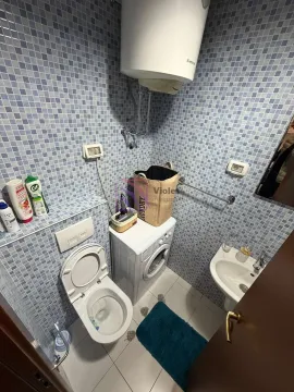 Smaller tiled bathroom with a toilet, washbasin, and washing machine. - image 5