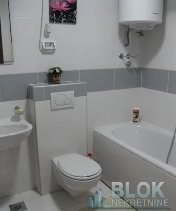 Compact bathroom with a bathtub, washbasin, and a wall-hung toilet.