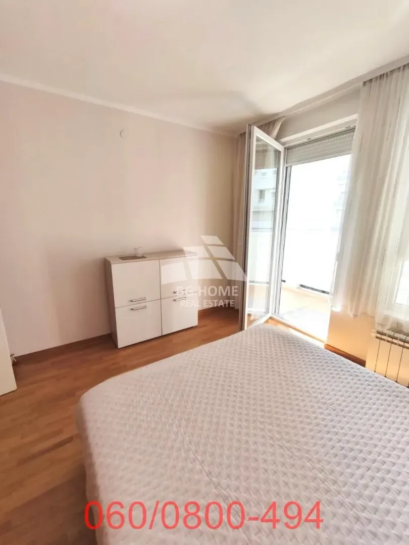 Nameštena spavaća soba sa bračnim krevetom i izlazom na terasu.