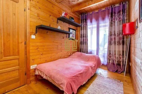 Small bedroom with wooden wall paneling and a bed covered with a pink bedspread. - image 7
