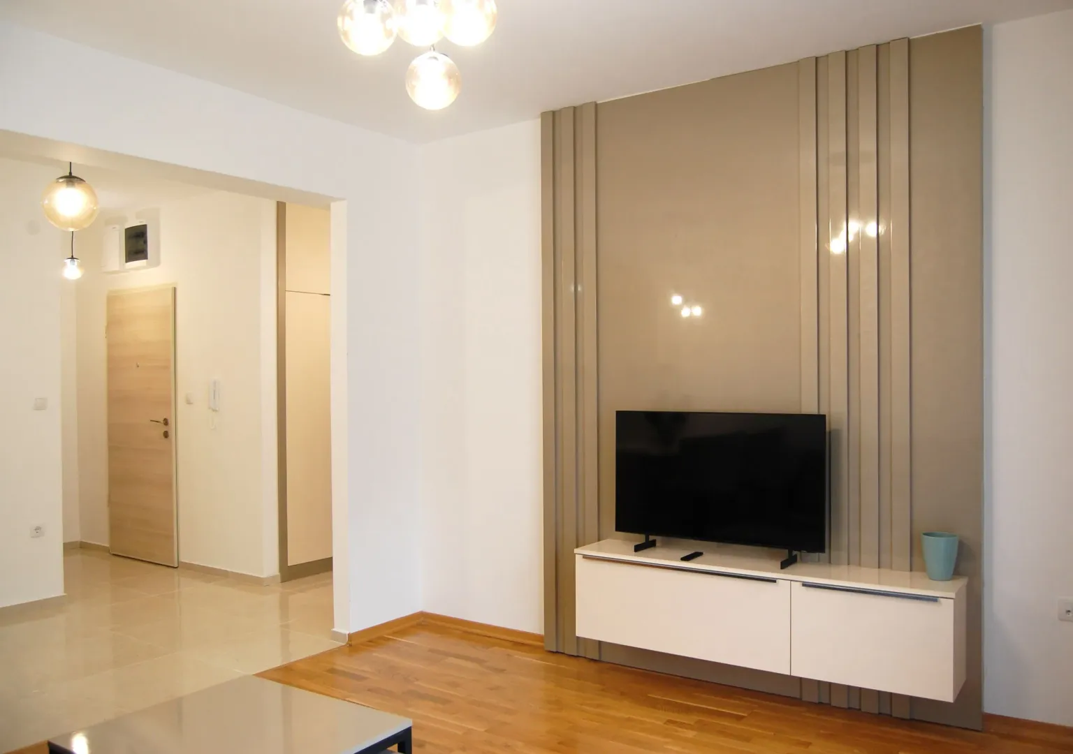 Living room with a TV unit and decorative wall panel.