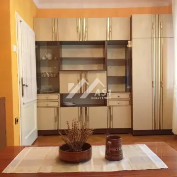 Dnevna soba sa velikim drvenim ormarom i stolom u prvom planu. - image 3