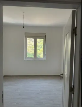 Pogled kroz vrata na praznu sobu sa bijelim zidovima i prozorom. - image 5
