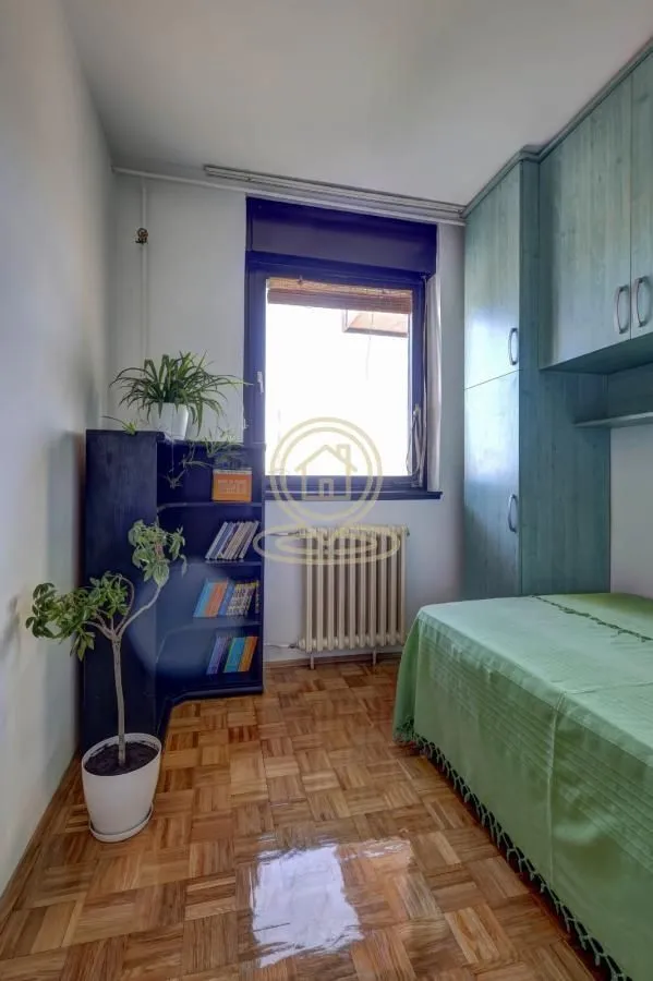 Small bedroom with a bed, wardrobe, and wooden flooring.