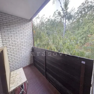 Natkriveni balkon sa drvenom ogradom i pogledom na zelenilo. - image 5