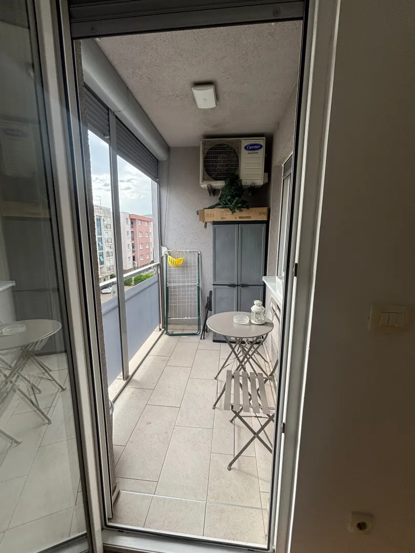Manji namješteni balkon sa stolom, stolicama i ostavom.