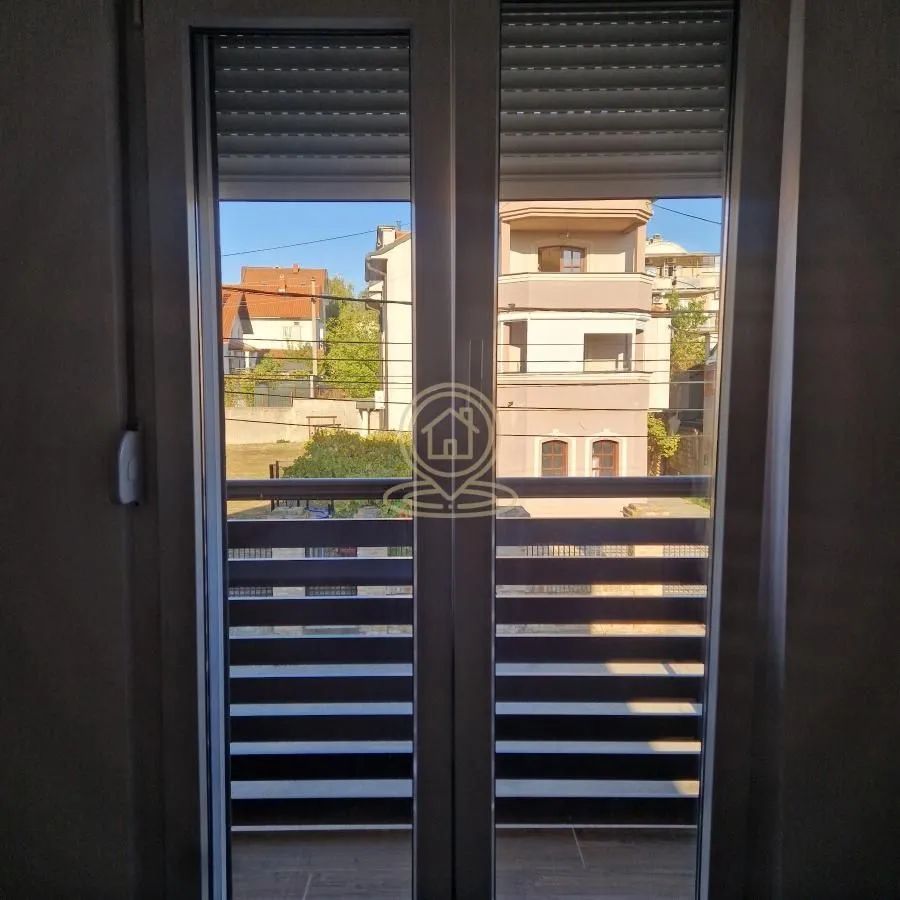 Pogled sa prozora na okolne zgrade i naselje.