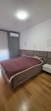 Spavaća soba sa bračnim krevetom, drvenim podom i klima uređajem. - image 5