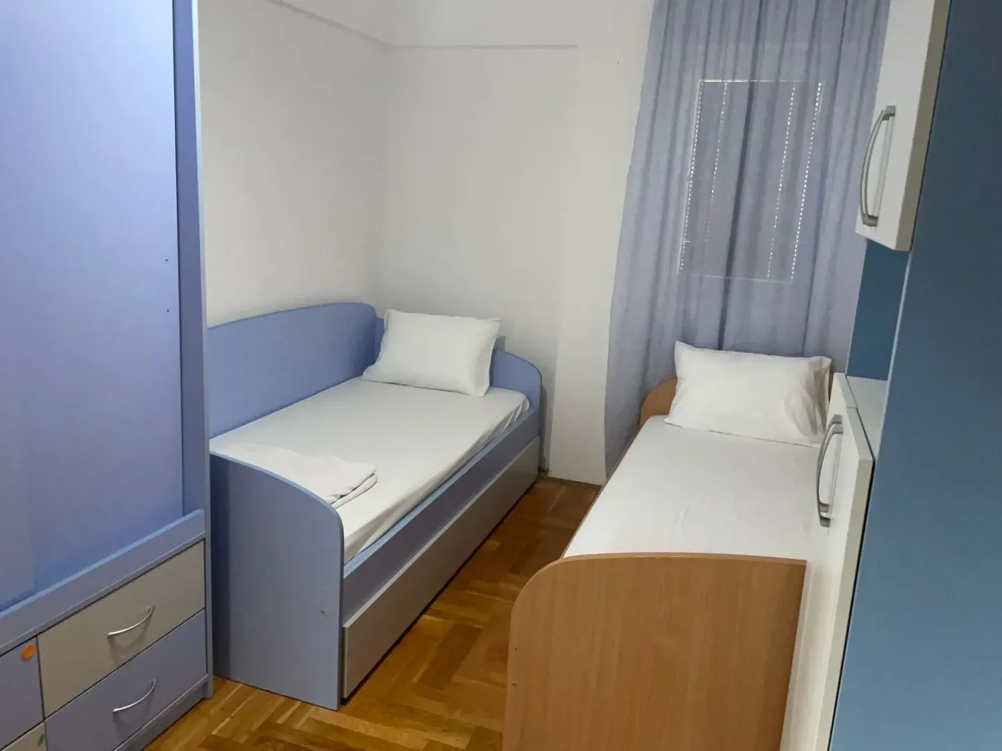 Dječija soba sa dva kreveta i garderoberom.