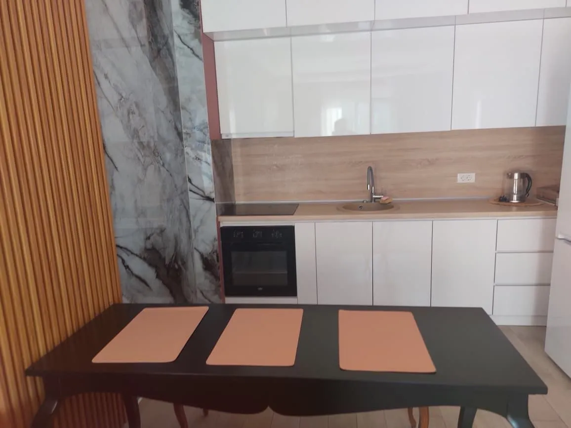 Modern kitchen with white cabinetry and a dining table in the foreground.