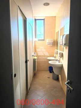 View of the bathroom with sinks, mirrors, and stalls on the left. - image 9