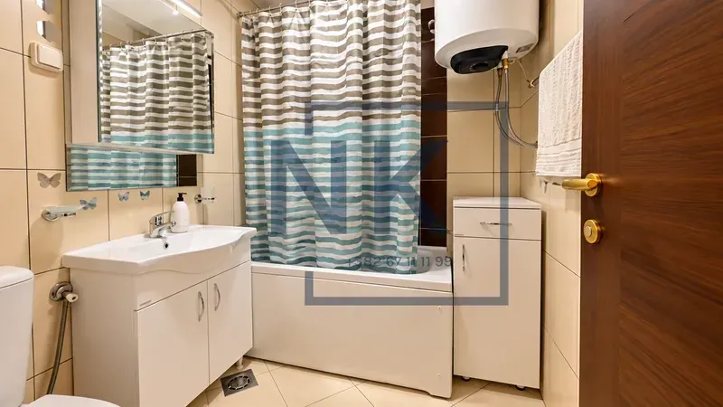 Bathroom equipped with a sink, a shower with a curtain, and a water heater.
