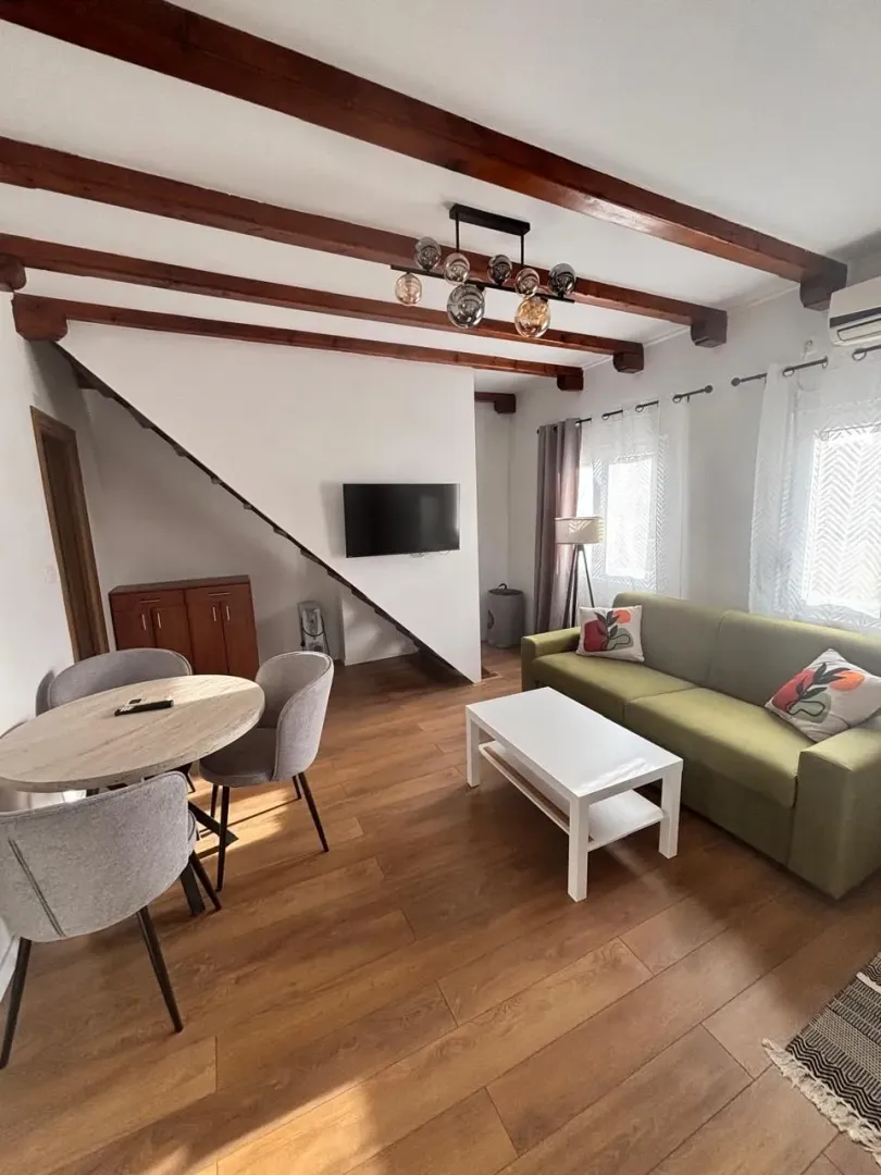 Living room with a dining area and wooden ceiling beams.