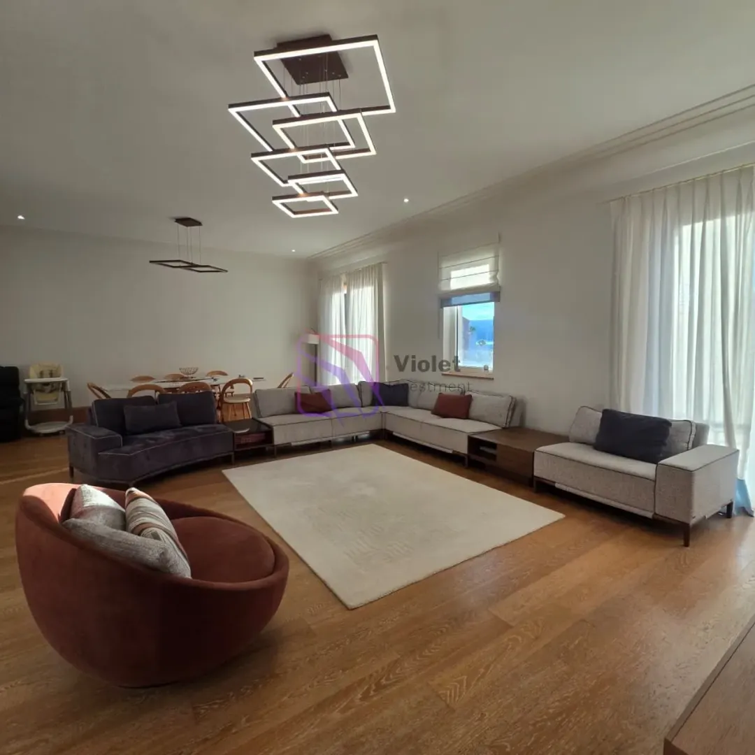 Spacious living room with a seating set and a dining area in the background.