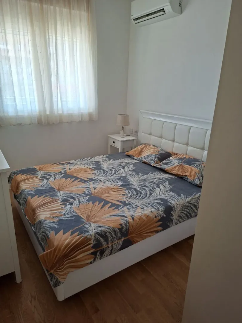 A bright bedroom featuring a double bed and an air conditioning unit.