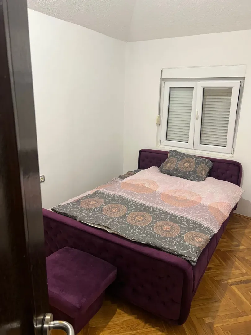 Manja spavaća soba sa bračnim krevetom i prozorom.