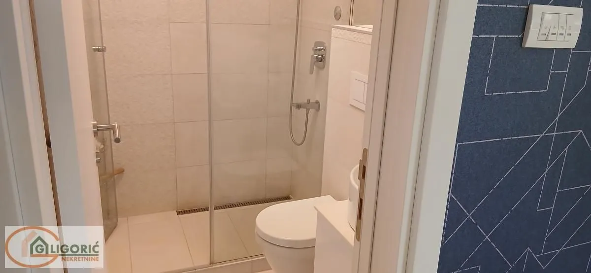 Pogled na moderno opremljeno kupatilo sa tuš kabinom i toaletom.