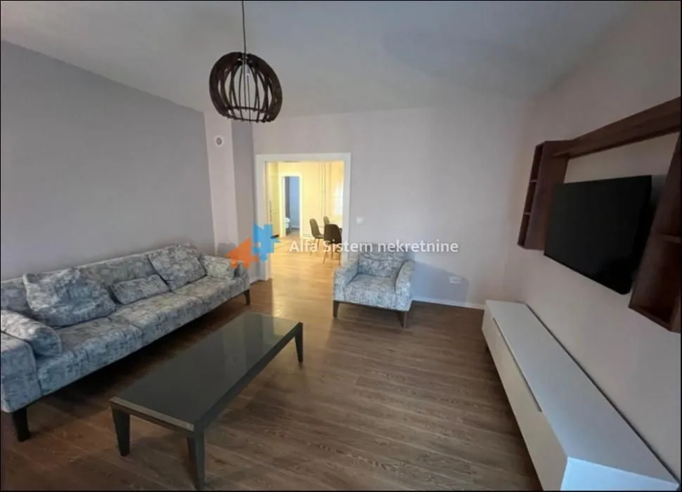 Living room with a sofa, coffee table, TV, and a view into the adjoining room.