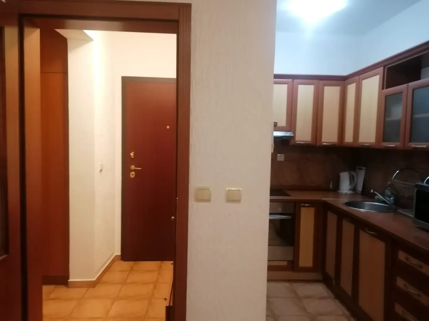 Pogled iz hodnika na kuhinju sa drvenimelementima.