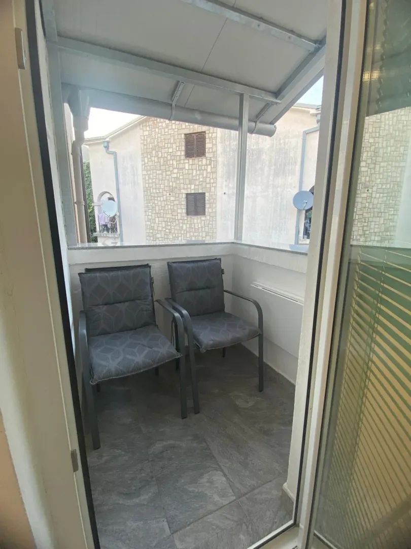 Manji natkriveni balkon sa dvije fotelje, pogled na okolne zgrade.